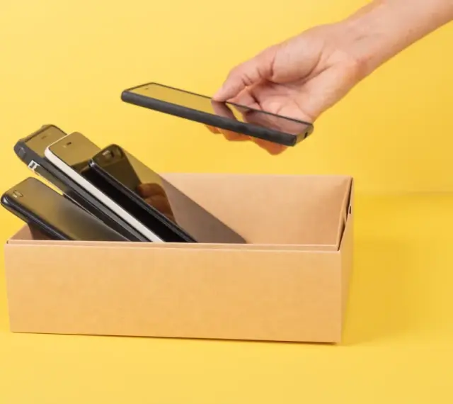 Ręka wkłada do kartonu kilka telefonów. Zastanawiam się, jaki mam model telefonu, bo wszystkie wyglądają podobnie.