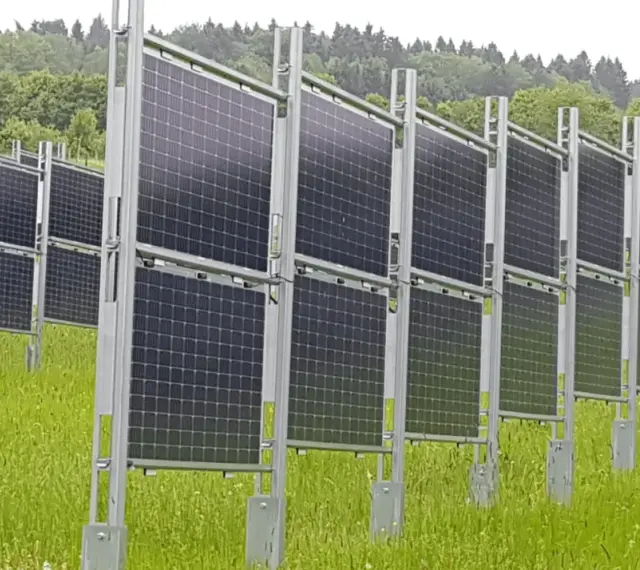 Rzędy wydajnych paneli fotowoltaicznych na tle zielonego lasu. Instalacja na łące, gotowa do produkcji czystej energii.
