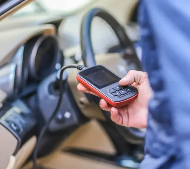 Diagnostyka Renault, być może błąd DTC B1267. Ręka trzyma urządzenie diagnostyczne podłączone do samochodu.