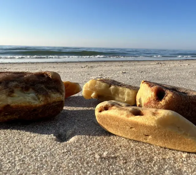 Jak rozpoznać bursztyn na plaży? Kilka kawałków bursztynu leży na piasku przy morzu.