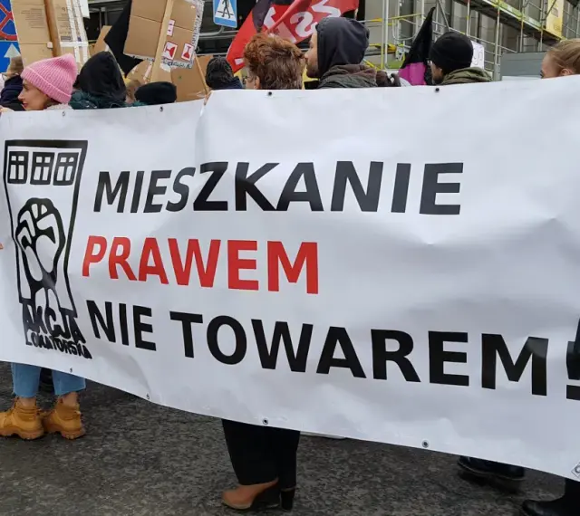 Protestujący niosą transparent "Mieszkanie prawem nie towarem!", domagając się ustaw chroniących lokatorów.