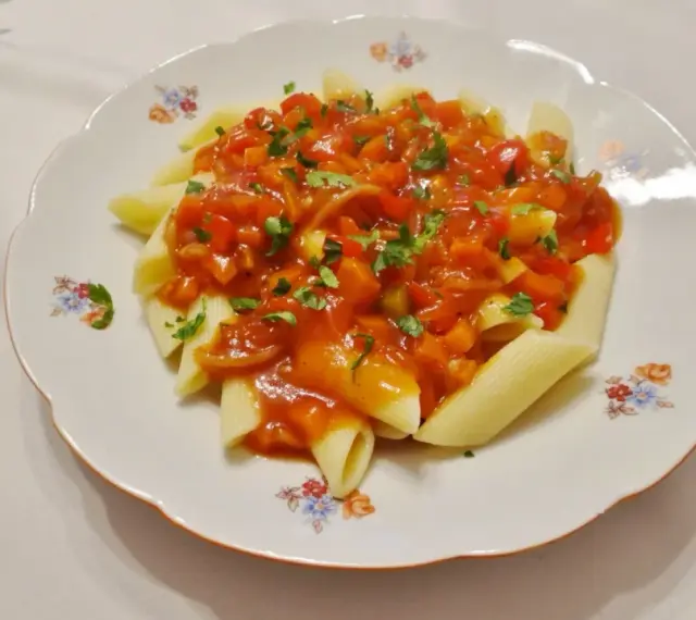 Penne z aromatycznym, słodko-kwaśnym sosem warzywnym, posypane świeżą natką pietruszki.