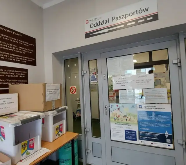 Oddział Paszportów w Zielonej Górze. W holu stoją pudła i pojemniki, a na drzwiach wiszą ogłoszenia.