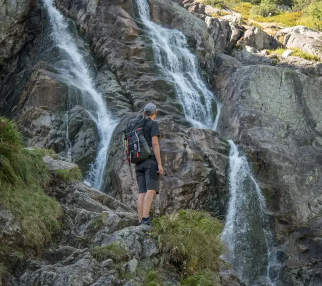 Turysta podziwia wodospad w Tatrach. Wspaniałe widoki, gdzie w Tatry warto się wybrać.