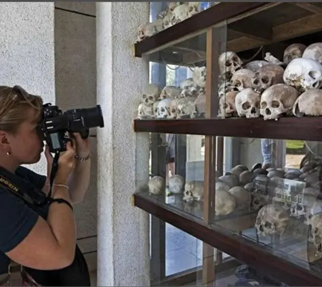 Kobieta fotografuje ludzkie czaszki na wystawie upamiętniającej pola śmierci w Kambodży.