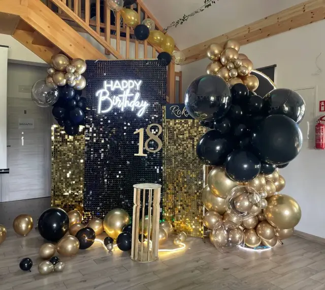 Elegancka ścianka do zdjęć na 18 urodziny z napisem "Happy Birthday" i liczbą 18, ozdobiona złotymi i czarnymi balonami.