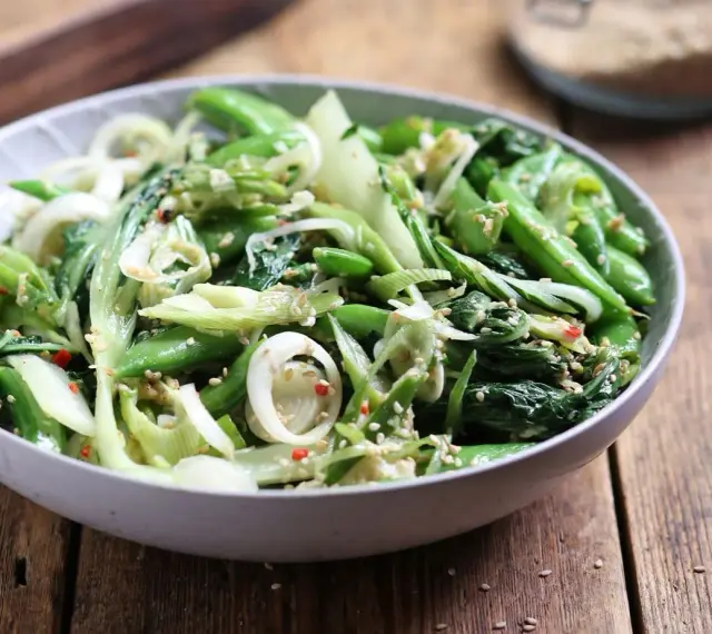Sałatka z pak choi, groszku cukrowego i cebuli dymki, posypana sezamem. Idealna do dań kuchni azjatyckiej, świetne przepisy na kapustę pak choi.