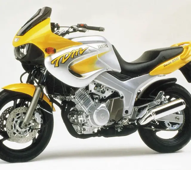 Żółto-srebrny motocykl Yamaha TDM 850 z charakterystycznym napisem "TDM" na baku. Gotowy na przygodę!