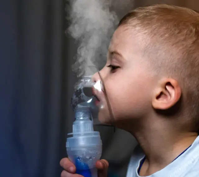 Chłopiec z maską inhalatora na twarzy, wdychający parę.