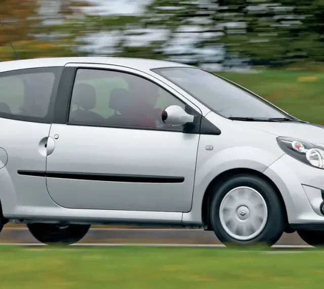 Srebrne Renault Twingo 2 w ruchu, z rozmytym tłem zieleni i drzew.