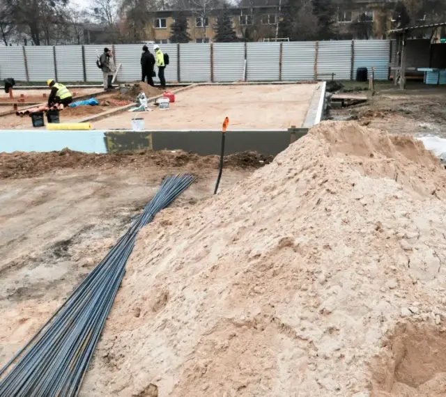 Budowa w marcu 2026. Działka z uregulowanym stanem prawnym, przygotowana pod fundamenty. Piasek, zbrojenie i pracownicy na placu budowy.