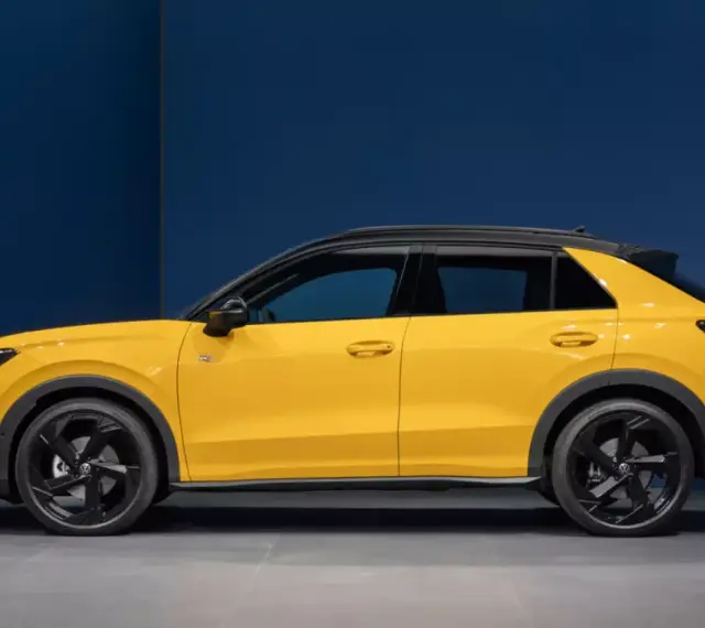 Nowy żółty Volkswagen T-Roc z czarnym dachem, widziany z boku.