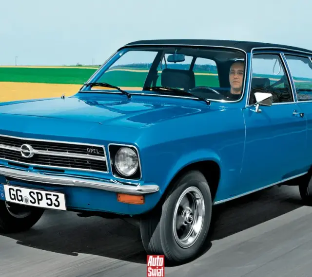 Niebieski Opel Ascona w wersji kombi jedzie po drodze, za nim pola i niebo.