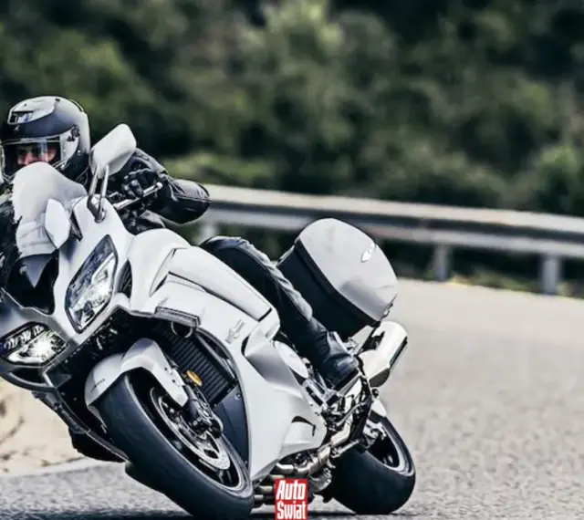 Motocyklista w białym Yamaha FJR 1300 na zakręcie drogi.