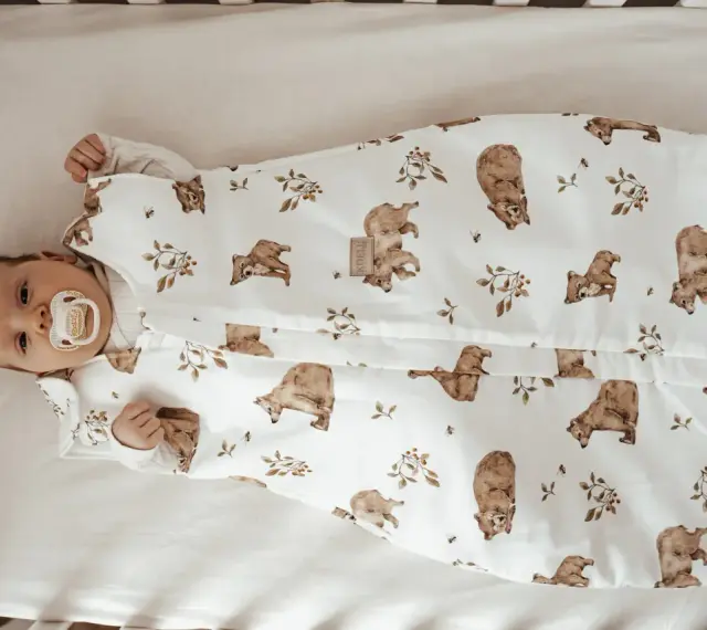 Niemowlę w śpiworku z misiami i pszczołami. Od kiedy kołderka dla niemowlaka jest tak urocza, sen staje się przyjemnością.
