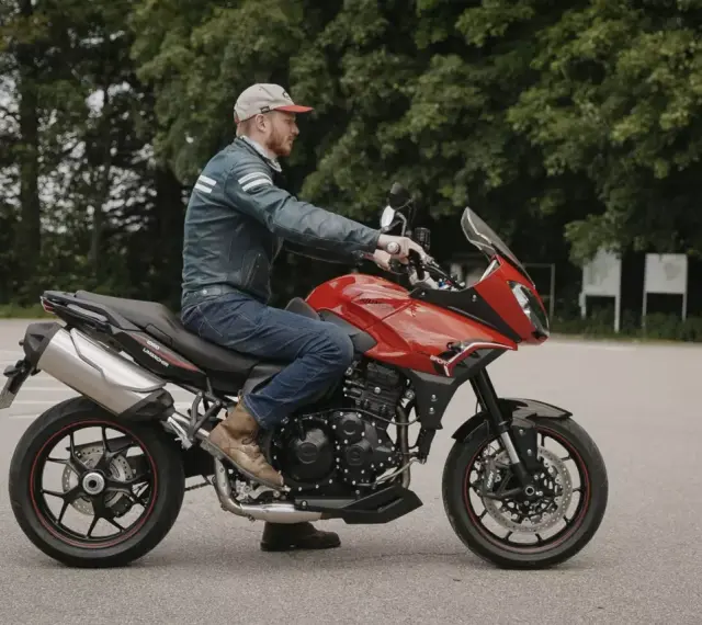 Mężczyzna na czerwonym motocyklu Triumph Tiger 1050. Poznaj jego dane techniczne i możliwości.