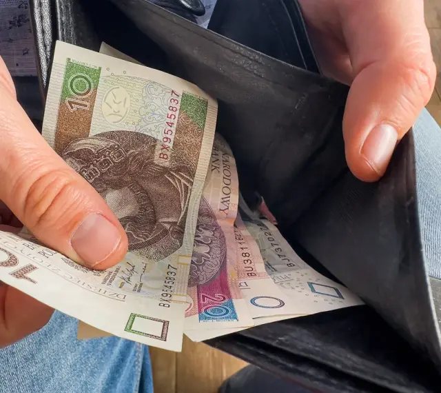Ręka wyciąga polskie banknoty z portfela. Czy to wyjaśnia, dlaczego w marcu 2026 r. limity dochodowe do dodatku mieszkaniowego wzrosły o 20 proc.?