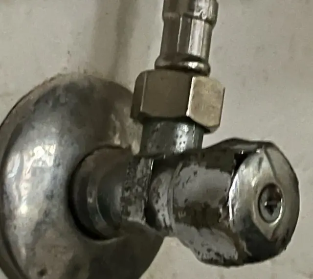 Metalowy zawór wodny, pokazujący, jak odkrecic zawor z woda. Widoczny śrubunek i pokrętło.