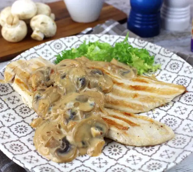 Sabroso pollo con champiñones en salsa cremosa, servido con lechuga fresca en un plato decorado.