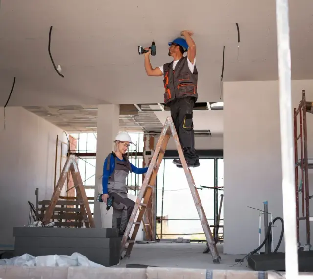 Dwóch budowlańców na drabinach montuje instalację elektryczną. Czy jest ulga na remont mieszkania?