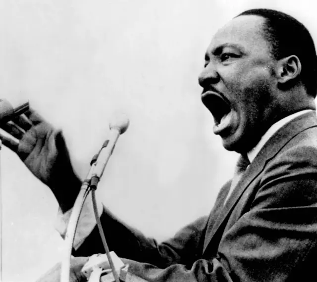 Martin Luther King przemawia z pasją do mikrofonu, jego głos niesie nadzieję i wolność.
