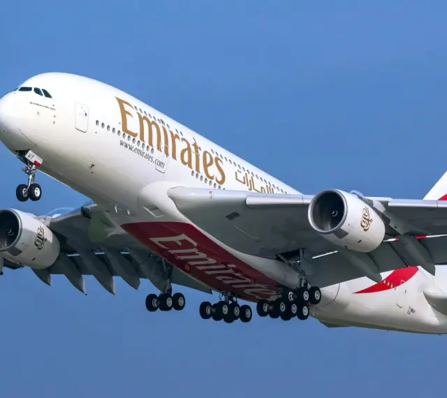 Airbus A380 Emirates z wieloma miejscami na pokładzie, wznoszący się na błękitne niebo.