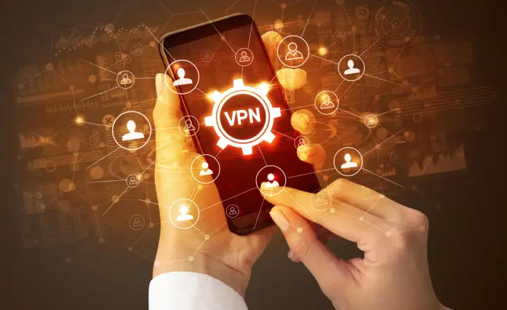 Dłonie trzymające smartfon z ikoną VPN i siecią połączeń użytkowników.