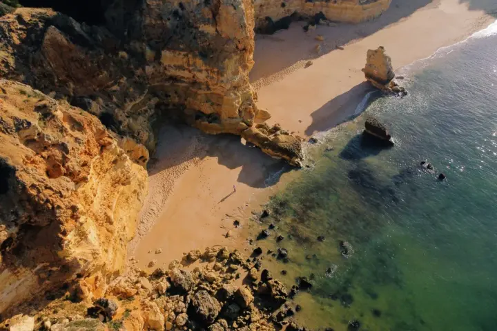 Malownicze klify i piaszczysta plaża w Portugalii. Morze o turkusowym odcieniu obmywa skaliste wybrzeże, tworząc idealne miejsce na spacer.