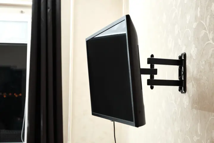 Czarny uchwyt telewizyjny na ścianie, z kablem TV. Idealna wysokość dla komfortowego oglądania.