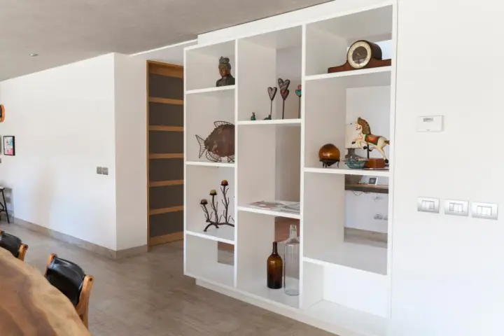Libreria in cartongesso, perfetta come divisorio per l'ingresso, con oggetti decorativi e un cavallo a dondolo.