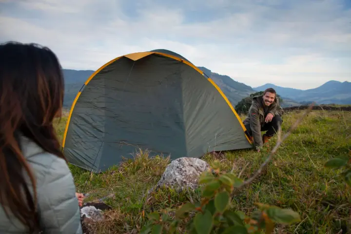 Mann und Frau biwakieren in Deutschland. Sie bauen ein Zelt in den Bergen auf, die Landschaft ist wunderschön.