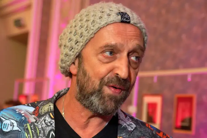 Nikodem Chabior w beżowej czapce i kolorowej kurtce, z zarostem, patrzy w bok.