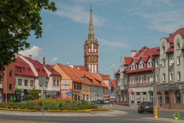 Kętrzyn atrakcje: malowniczy rynek z charakterystyczną wieżą kościelną, kolorowe kamienice i zielone skwery.