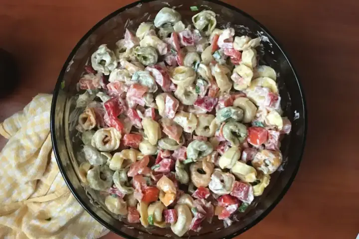 Kolorowa sałatka z tortellini, papryką i majonezem w szklanej misce.