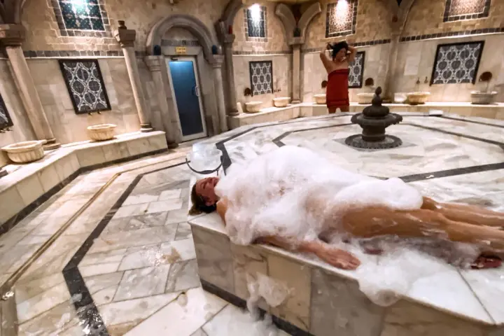 Kobieta w pianie w łaźni hammam. To tradycyjne tureckie łaźnie parowe, miejsce relaksu i oczyszczenia.
