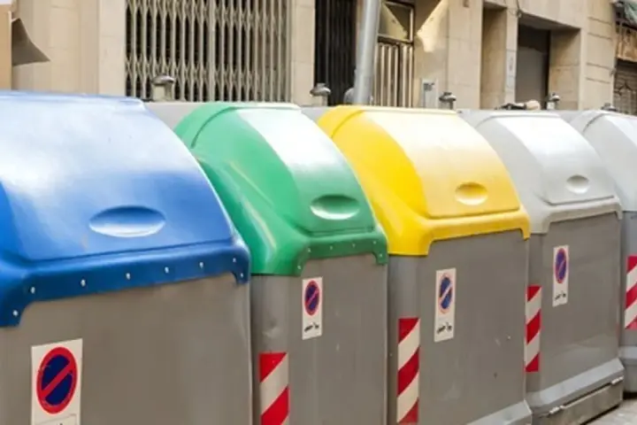 Fila de contenedores de reciclaje de Ecoembes en la calle: azul, verde, amarillo y grises.