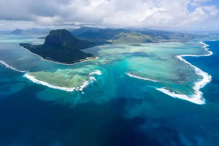 Majestatyczny Le Morne Brabant góruje nad turkusową laguną Mauritiusa. Woda mieni się odcieniami błękitu i zieleni, a białe fale rozbijają się o rafę.