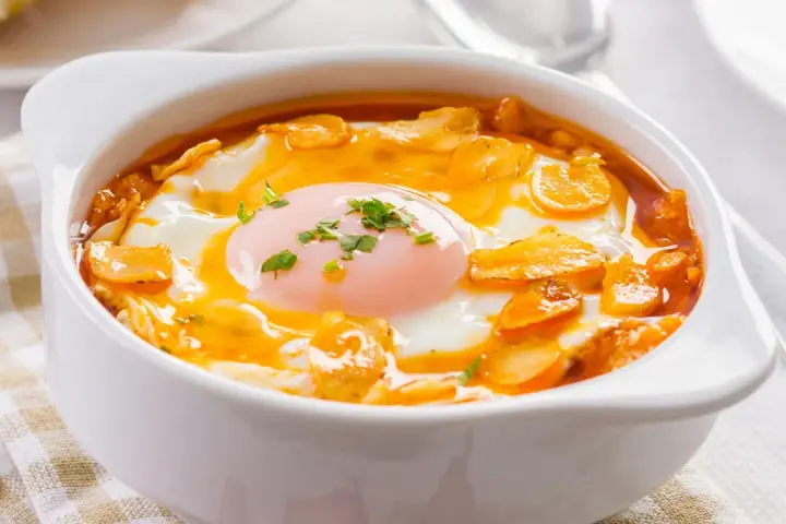 Sopa castellana en cuenco blanco con huevo escalfado y picatostes.