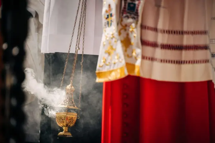 Złota kadzielnica unosi dym podczas uroczystości. W tle widać szaty liturgiczne, przypominające o święta nakazane.