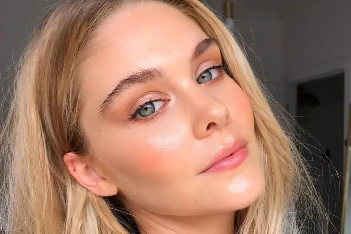 Blondynka z zielonymi oczami, z subtelnym rumieńcem i błyszczącymi ustami. Wygląda naturalnie, jakby miała make up no make up.