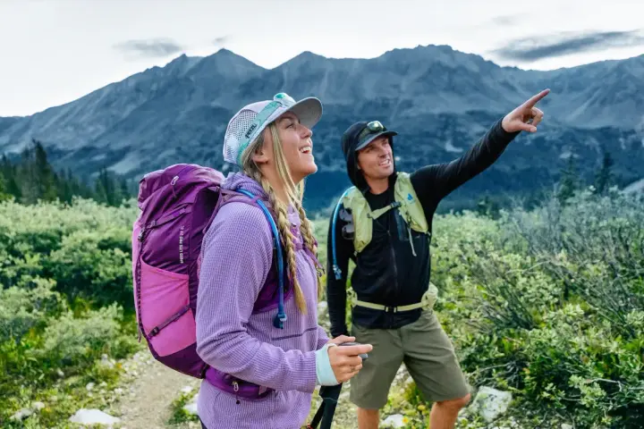 Deux randonneurs s'émerveillent devant un panorama de amm montagne. L'un d'eux pointe du doigt un sommet lointain.
