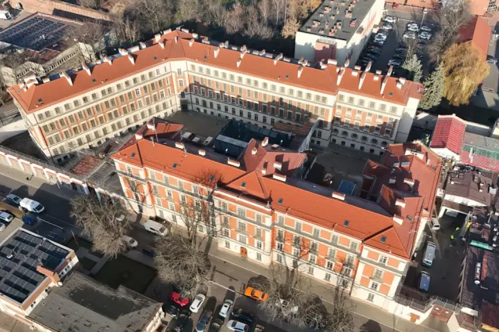 Widok z lotu ptaka na zakład karny Montelupich. Widać budynki z czerwonymi dachami, ogrodzenie z drutem kolczastym i parking. Odwiedziny w zakładzie karnym.