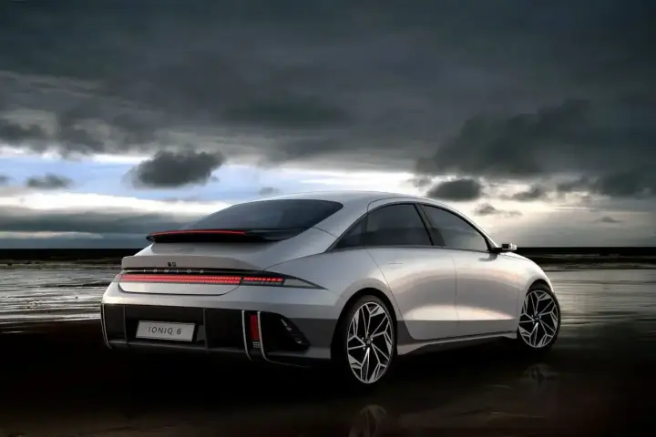 Srebrny Hyundai Ioniq 6 na plaży pod pochmurnym niebem.