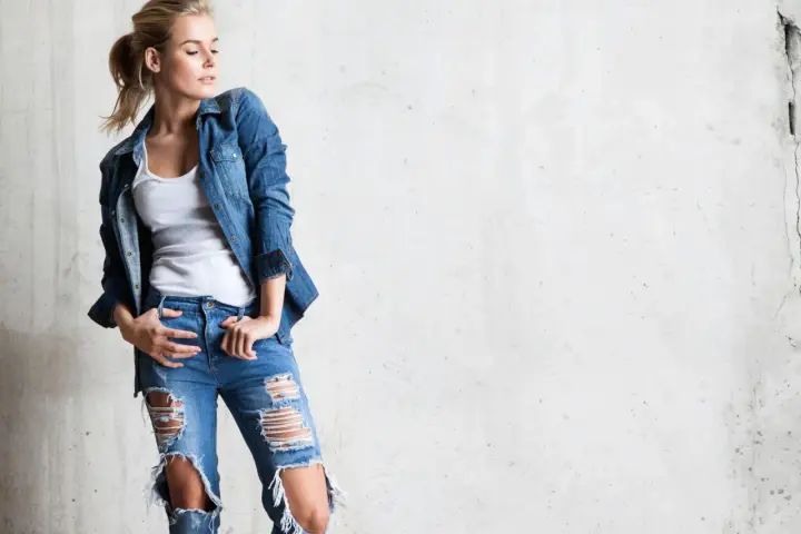 Stylowa blondynka w rozdartych jeansach i jeansowej koszuli. Inspiracja, jak nosić koszulę do jeansów.