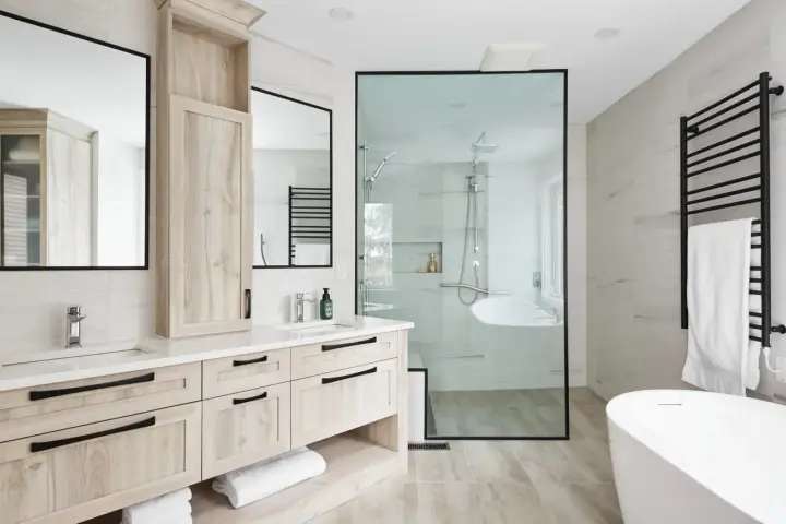 Salle de bain moderne avec double vasque en bois clair, douche vitrée et baignoire îlot. Un design épuré pour une ambiance zen.