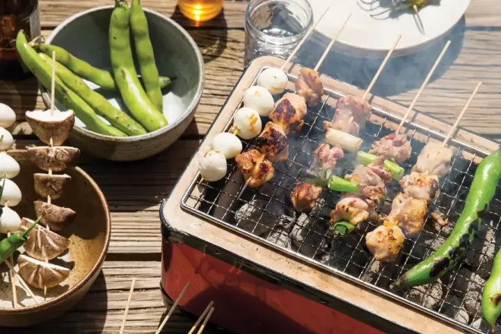 Grillowane **yakitori** z kurczakiem i warzywami, obok miska fasolki i grzybów na patyczkach.