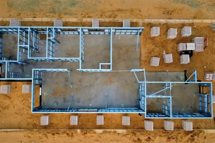 Estructura metálica de una casa en construcción. Se aprecian materiales apilados, listos para el montaje. El precio de hacer un sótano puede variar.