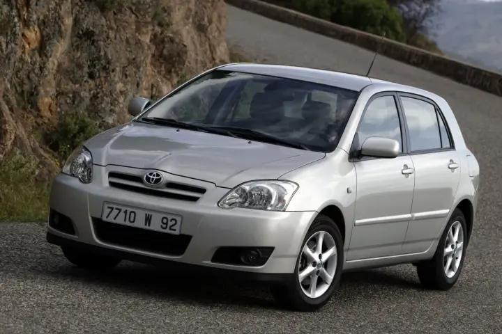 Srebrna Toyota Corolla E12 na krętej drodze, z kamienistym zboczem w tle.