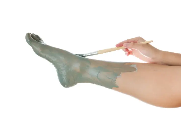 Application d'un masque d'argile sur un pied, comme un soin pour un clou au pied.