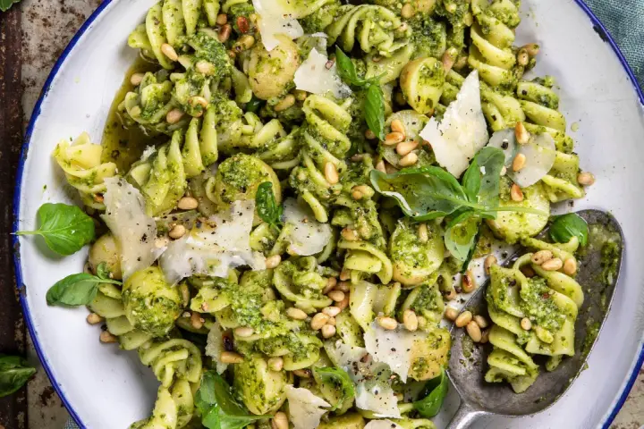 En närbild av en härlig pastasallad med pesto, pinjenötter, parmesan och färsk basilika. Perfekt för en lätt lunch.